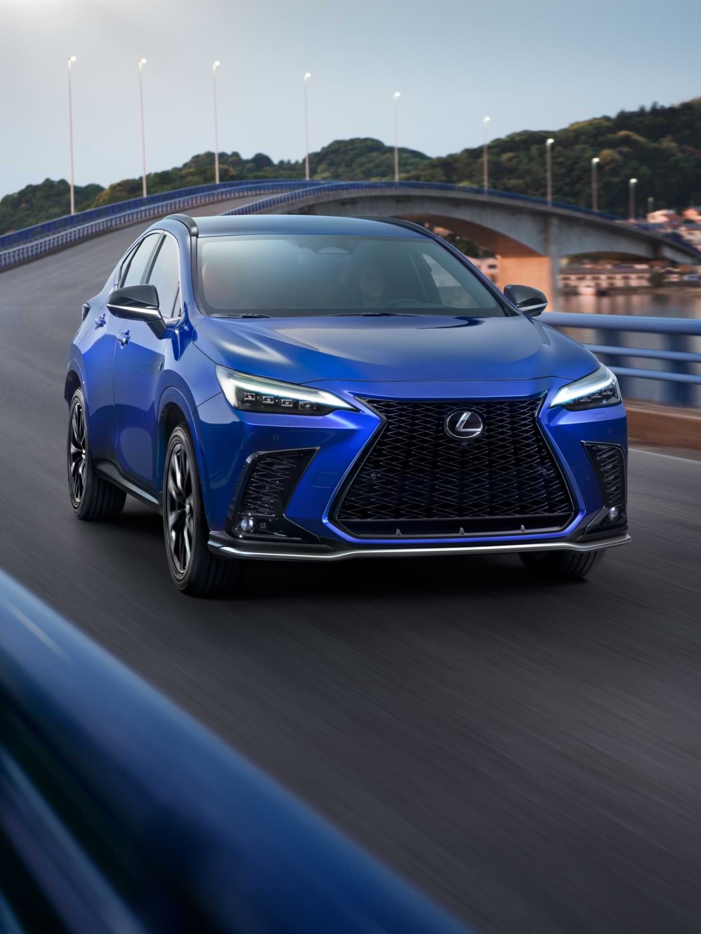 Blue 2021 Lexus NX driving over a bridge