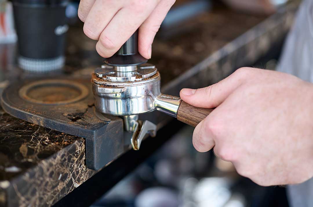 A baristia prepares a cup of coffee using a St Remio branded milk jug